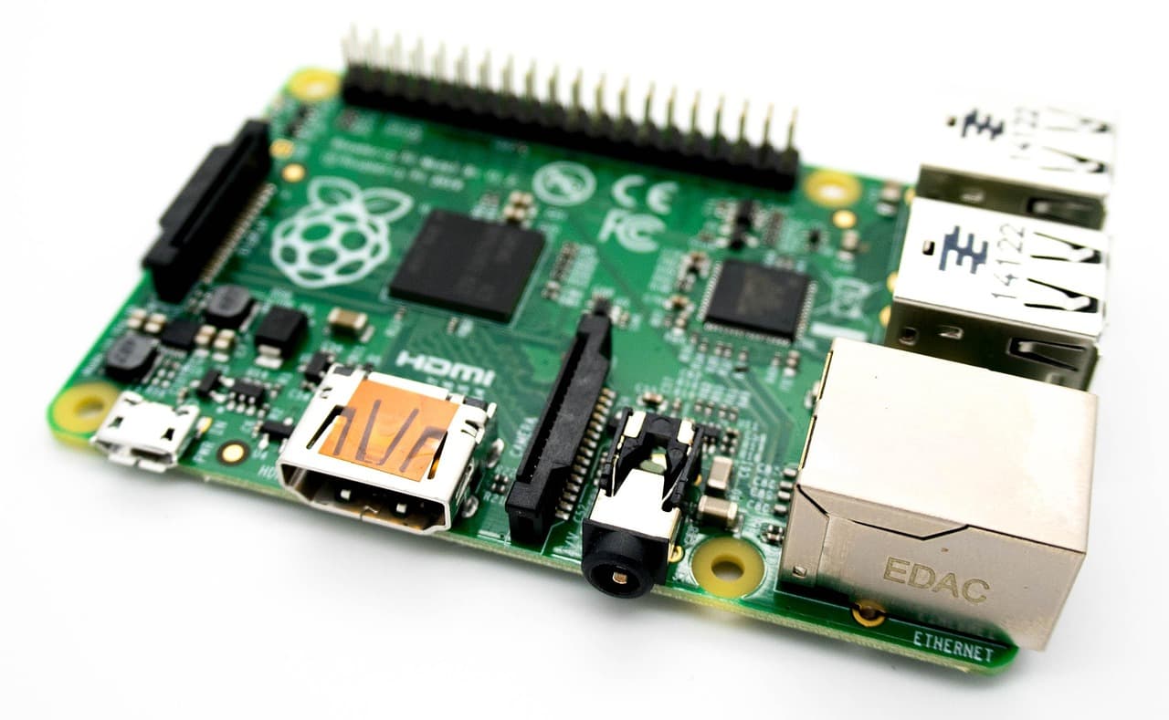 Une carte Raspberry Pi nue posée sur fond blanc, circuit imprimé vert, rangée de broches GPIO noire, ports USB et prise ethernet marquée EDAC.