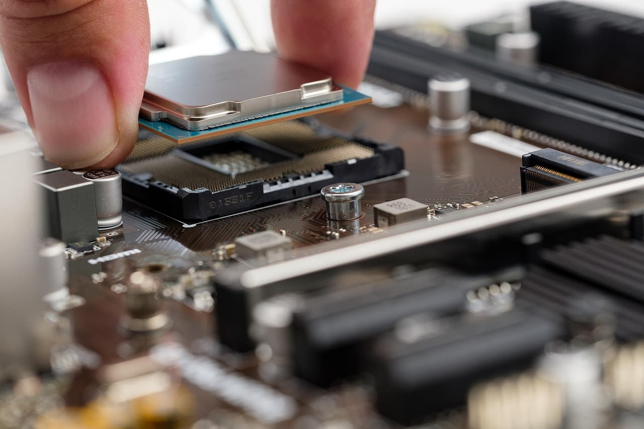 Primer plano de una placa base y un socket de CPU sobre una mesa de trabajo