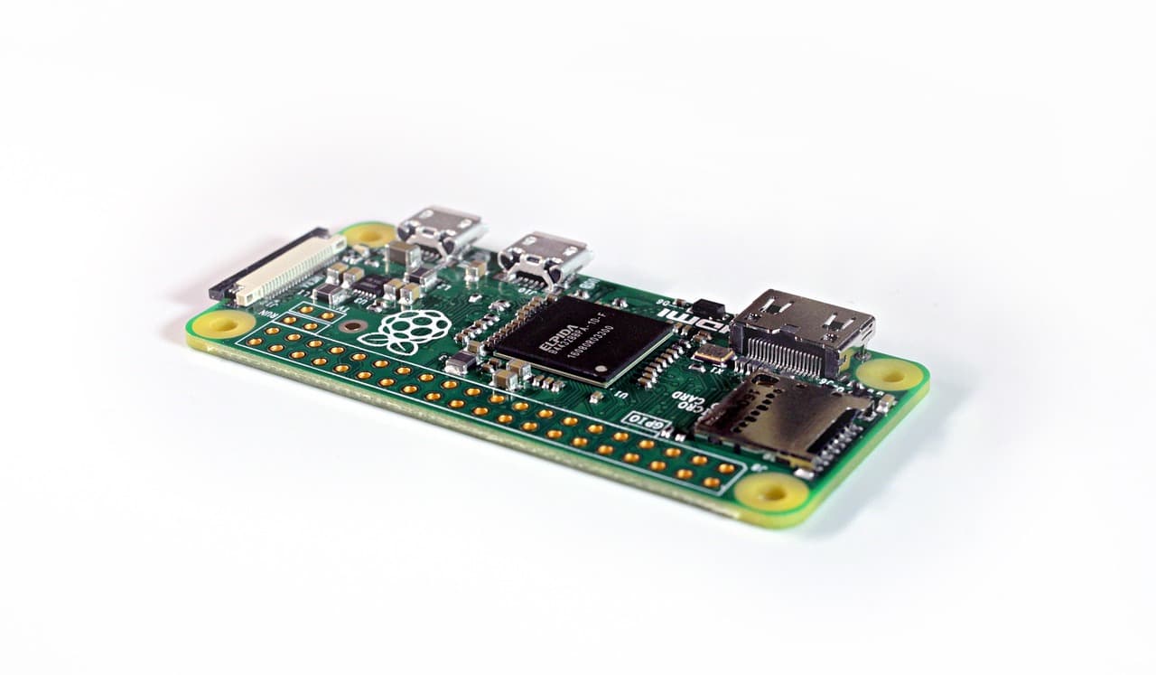 Une carte Raspberry Pi Zero nue, de couleur verte, photographiée sur fond blanc, montrant le logo framboise, deux ports micro USB, un port mini HDMI, un emplacement microSD et une rangée de trous GPIO non soudés.