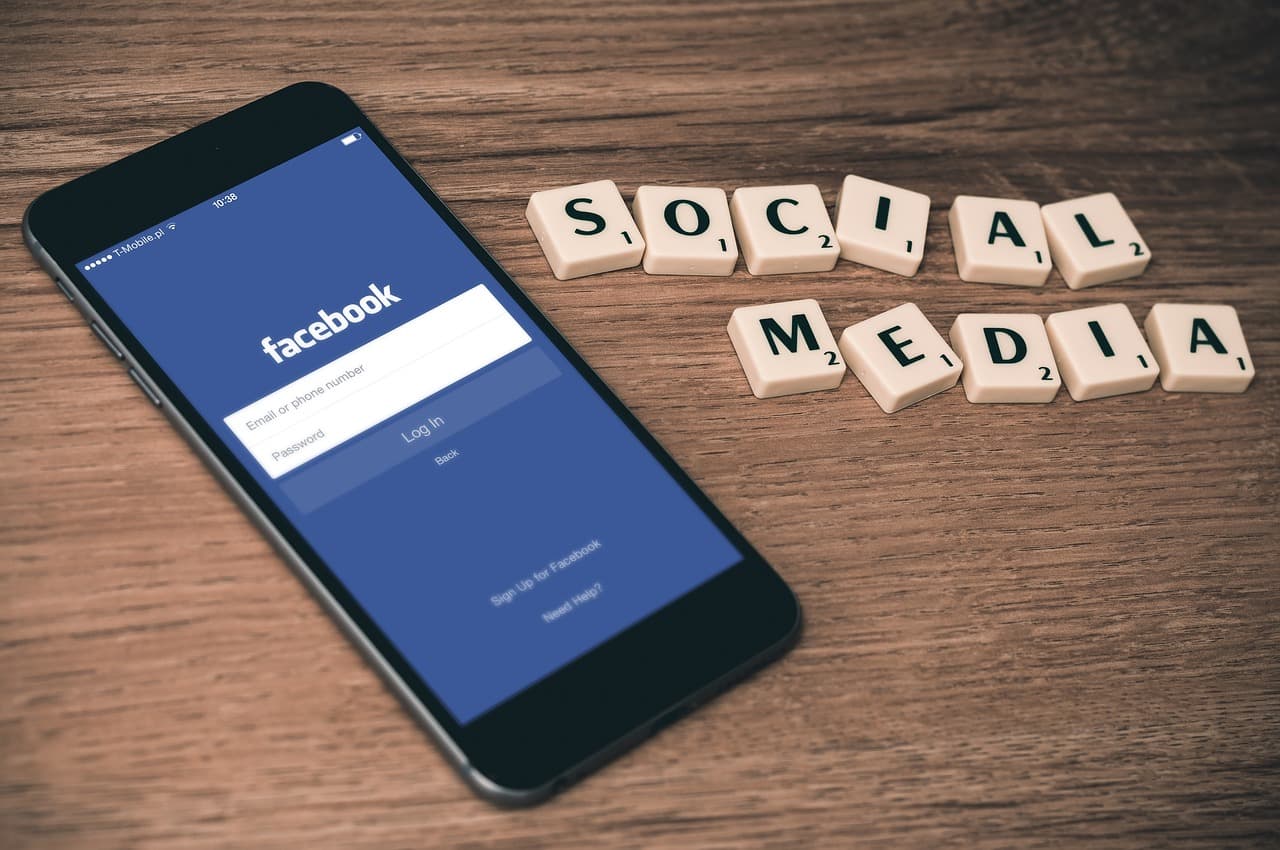 Um smartphone que mostra um ecra de inicio de sessao numa rede social ao lado de placas que formam as palavras 'social media'